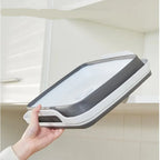 Hand holding a gray and white air filter against a kitchen background