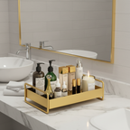 Bathroom counter with skincare products and a candle on a gold tray, reflected in a mirror.