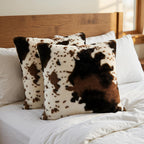 Cow print pillows on a bed with a wooden headboard.