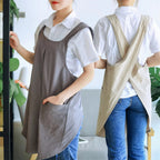 Two people wearing aprons in a home setting with plants.
