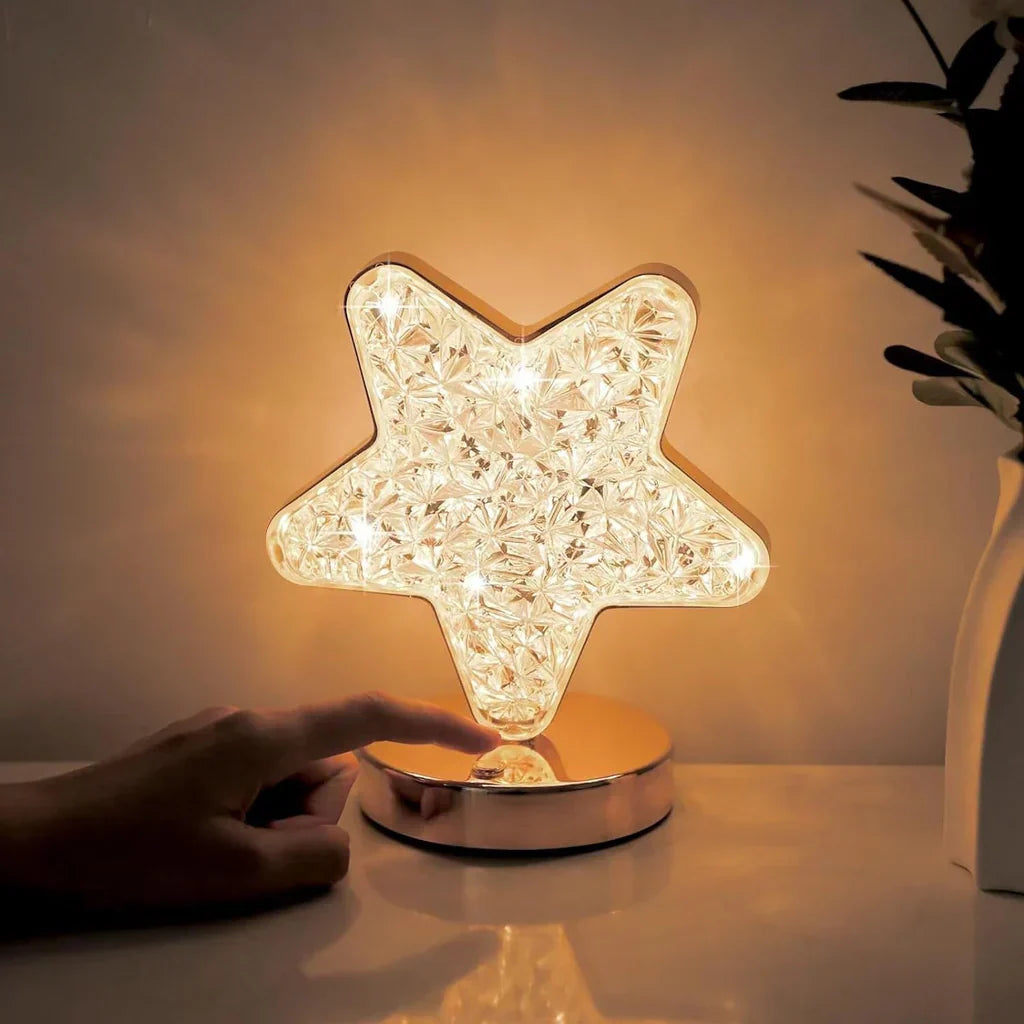 Star-shaped lamp with a hand touching it on a reflective surface.