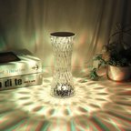 Decorative crystal vase on a textured surface with books and a plant in the background