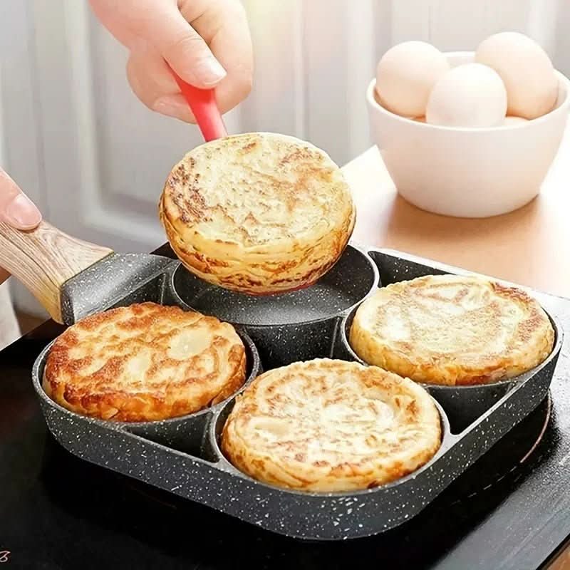 Person using a spatula to lift a pancake out of a four-sectioned pan with eggs in the background.