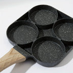A black non-stick four-cup pan with a light wood handle, shown on a clean white background.