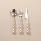 Silver cutlery set with pearl handles on a beige background