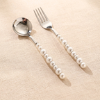 Spoon and fork with pearl handle on a beige background