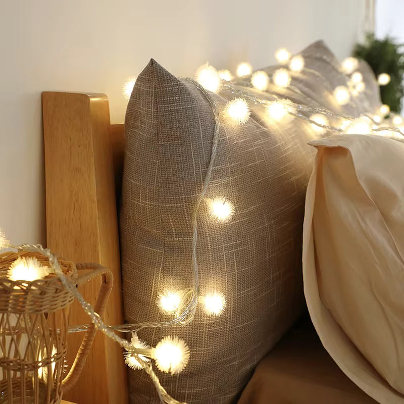 Decorative pillows with string lights on a bed