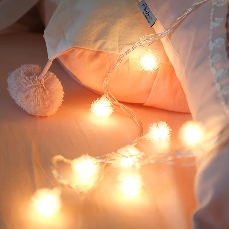 String lights with pom-pom ends on a soft surface