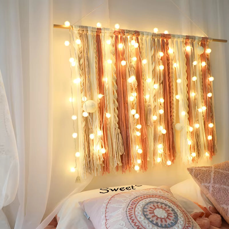 String lights draped over a curtain with a cozy bed in the foreground
