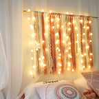 String lights draped over a curtain with a cozy bed in the foreground