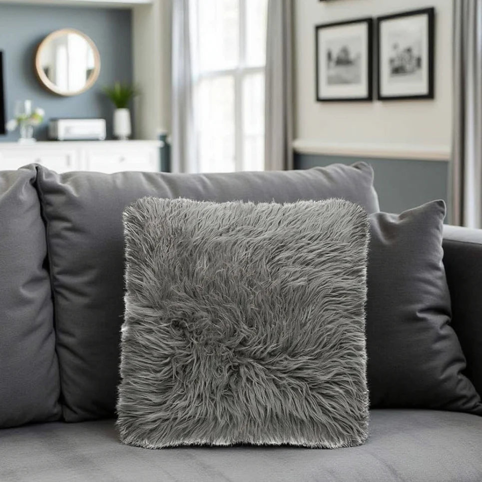 Gray fluffy pillow on a gray sofa in a living room setting.