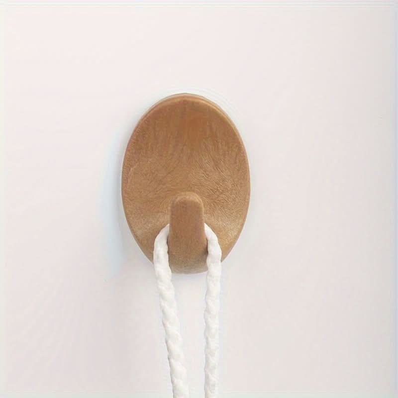 Wooden wall hook with a white rope on a light pink background