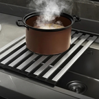 Brown pot on a stovetop with steam rising, set against a kitchen background.
