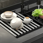 Kitchen sink with a drying rack holding dishes and a person washing vegetables.