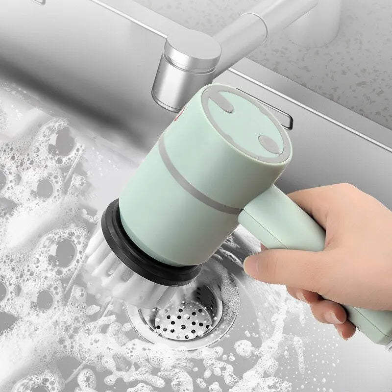 Hand using a green kitchen brush to clean a sink
