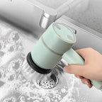Hand using a green kitchen brush to clean a sink