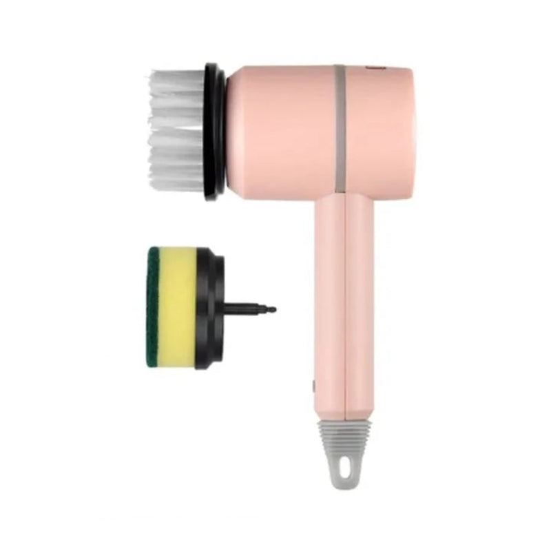 A pink handheld electric brush cleaner with a white bristle attachment and a separate green and yellow sponge pad, shown on a plain white background.