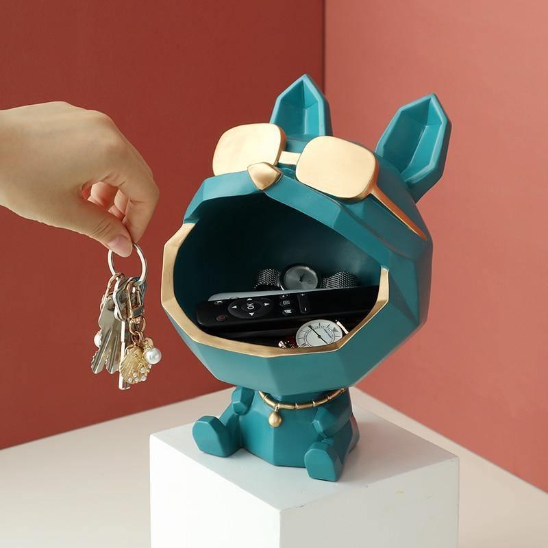 Teal and gold cat-shaped key organizer with a hand placing keys inside against a red background