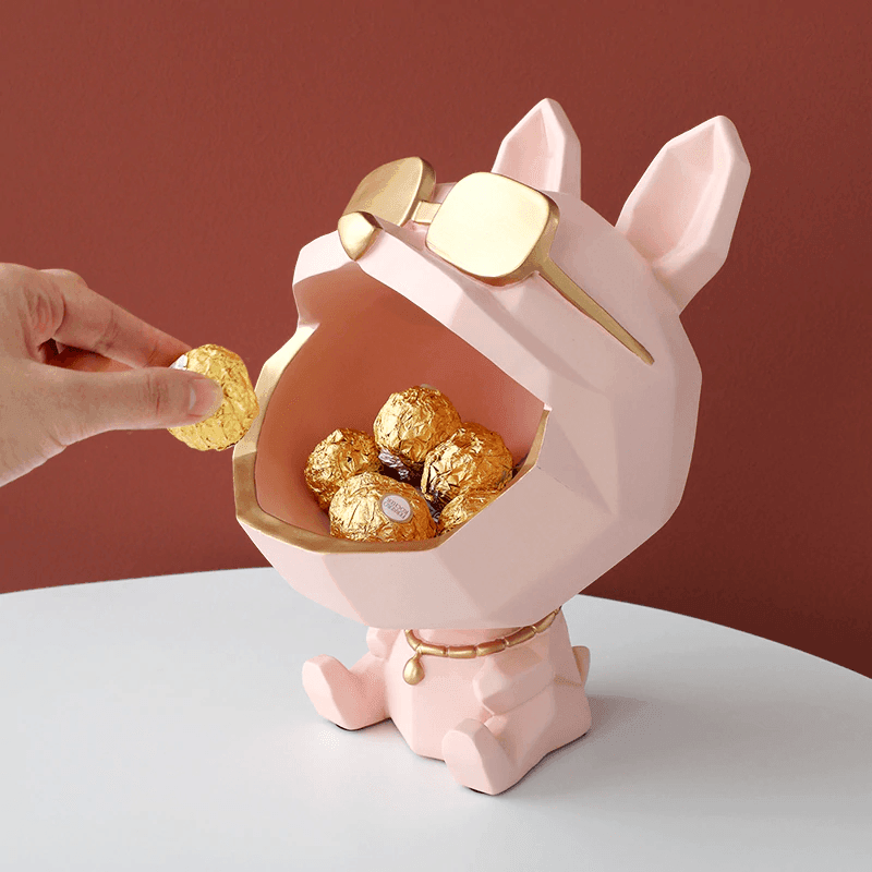 Pink dog-shaped container with gold interior holding chocolate eggs, against a red background.