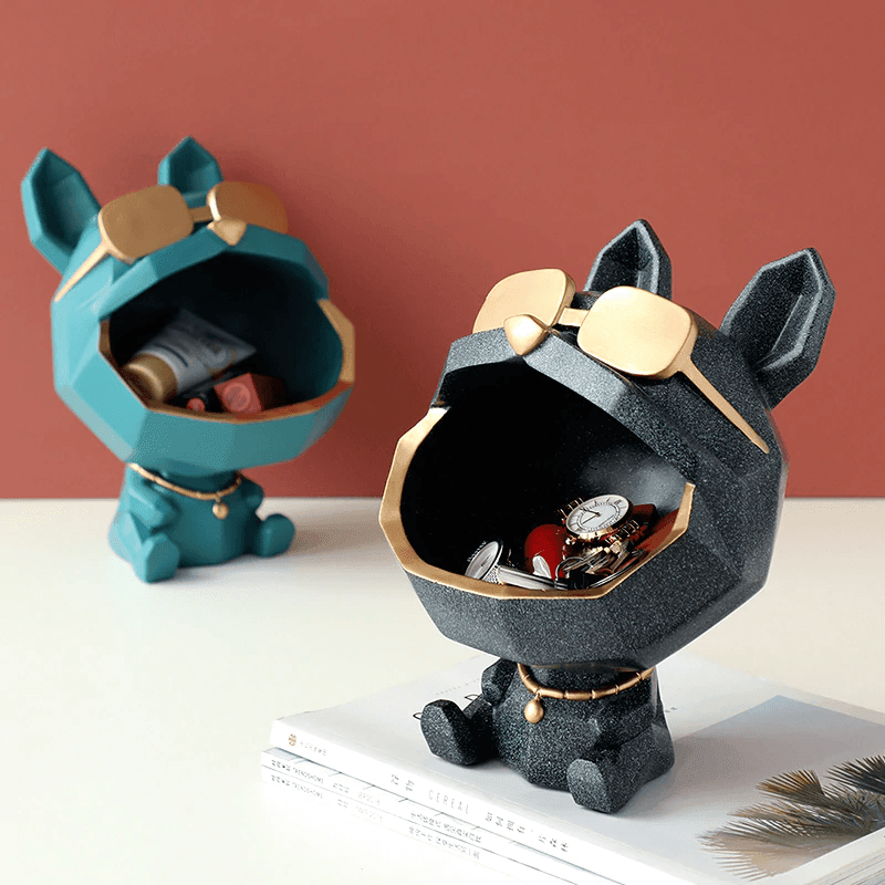 Two decorative animal-shaped containers, one blue and one black, on a surface with a red background.