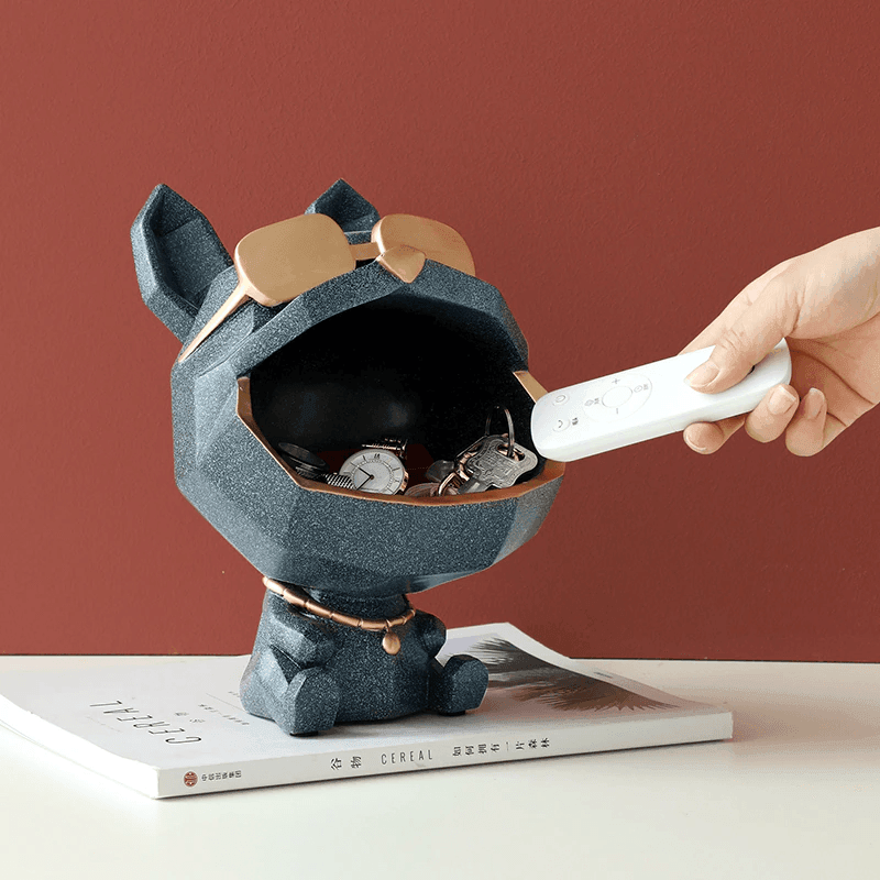 Dog-shaped key holder with a hand placing a remote control inside on a red background