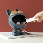 Dog-shaped key holder with a hand placing a remote control inside on a red background