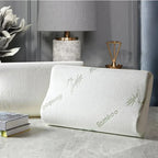 White pillow with bamboo text on a gray surface, with a lamp and books in the background.