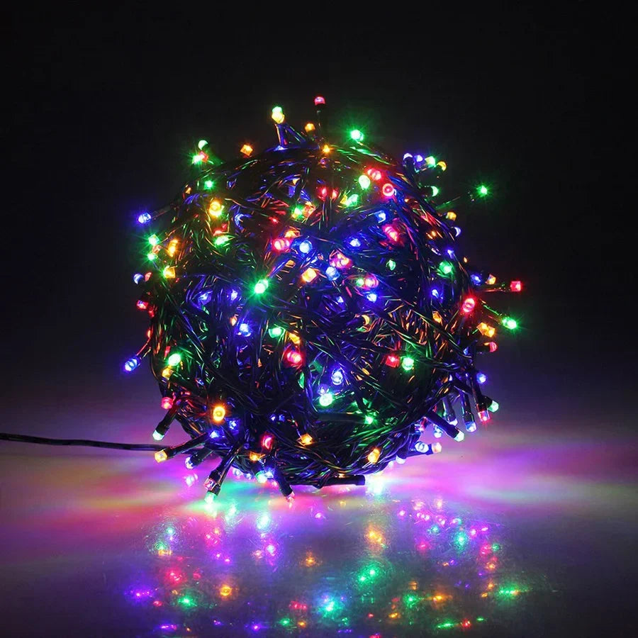 Multicolored string lights on a reflective surface with a dark background