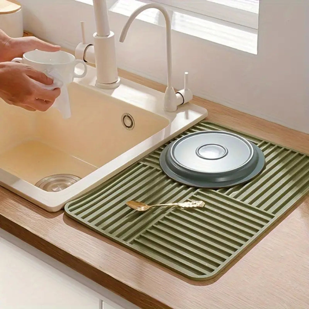 Green kitchen mat on a wooden countertop with a sink and faucet in the background.