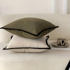 Two textured pillows stacked on a surface with a cup and saucer in the background.