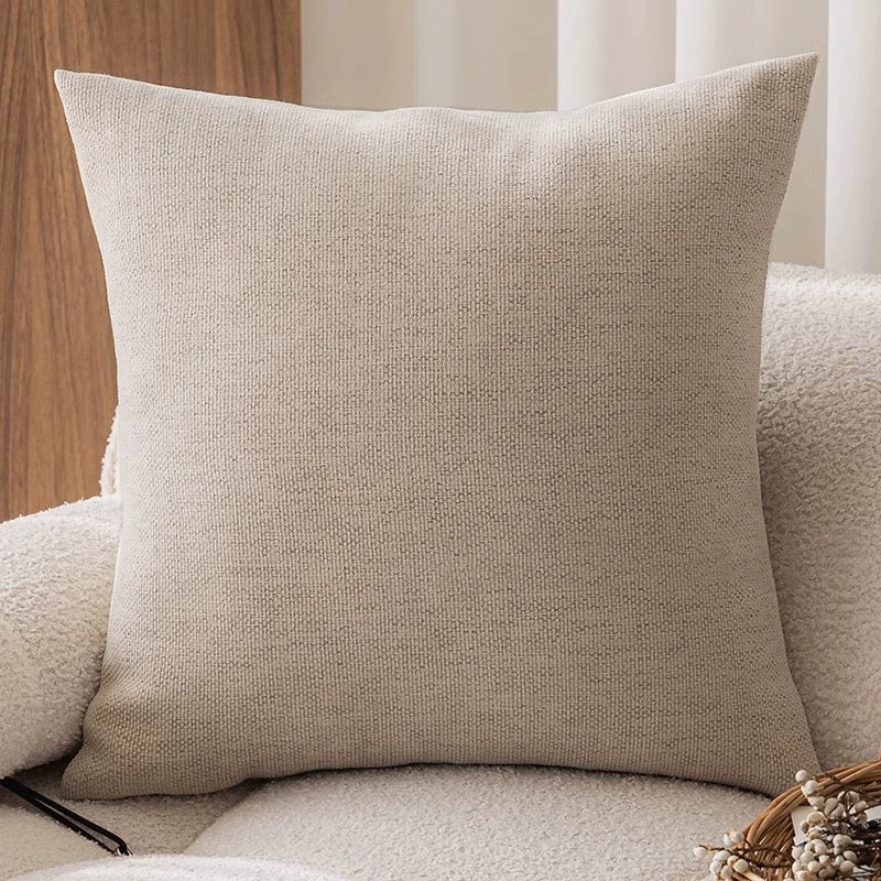 Beige textured pillow on a sofa with a neutral background