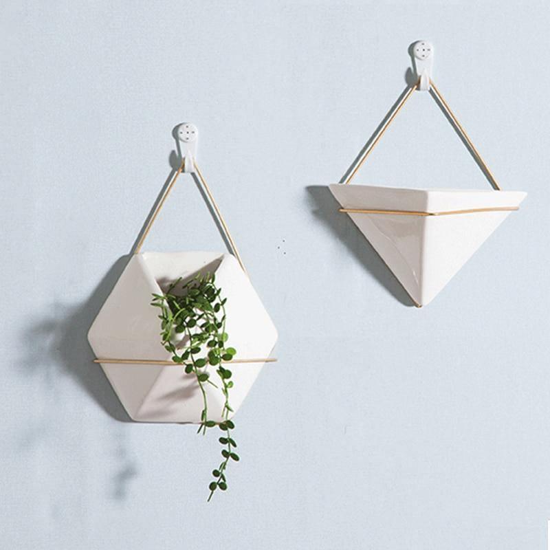 Two geometric wall planters with plants on a light blue background