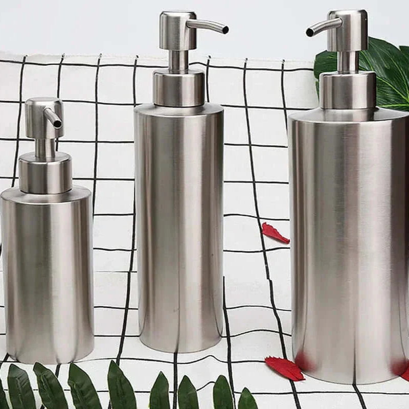 Three metallic soap dispensers on a checkered background with leaves.