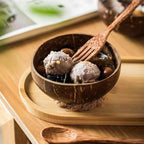 Coconut shell bowl with dessert on a wooden tray