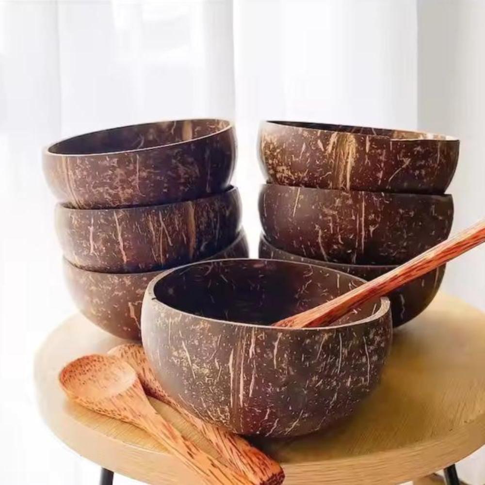 Set of coconut bowls with wooden spoons on a light background