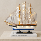 Model ship with lights on a book titled 'The Sea and its Vessels' against a beige background