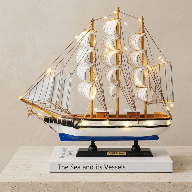 Model ship with lights on a book titled 'The Sea and its Vessels' against a beige background