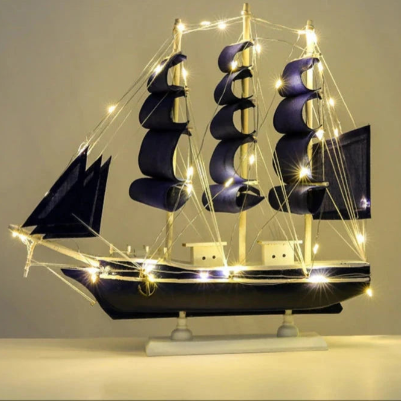 Model ship with purple sails and string lights on a gray background