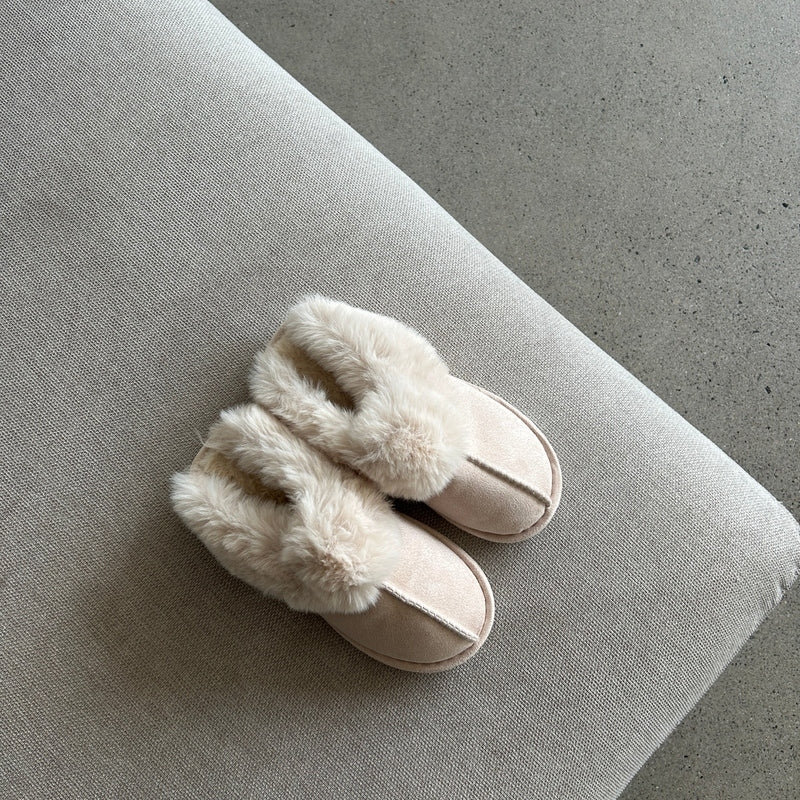 Pair of white slippers with fluffy fur trim on a gray surface