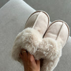 Beige slippers with fluffy fur on a gray surface