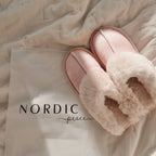 Pair of pink slippers with fluffy fur lining on a blanket, featuring the brand 'Nordic Peace'.