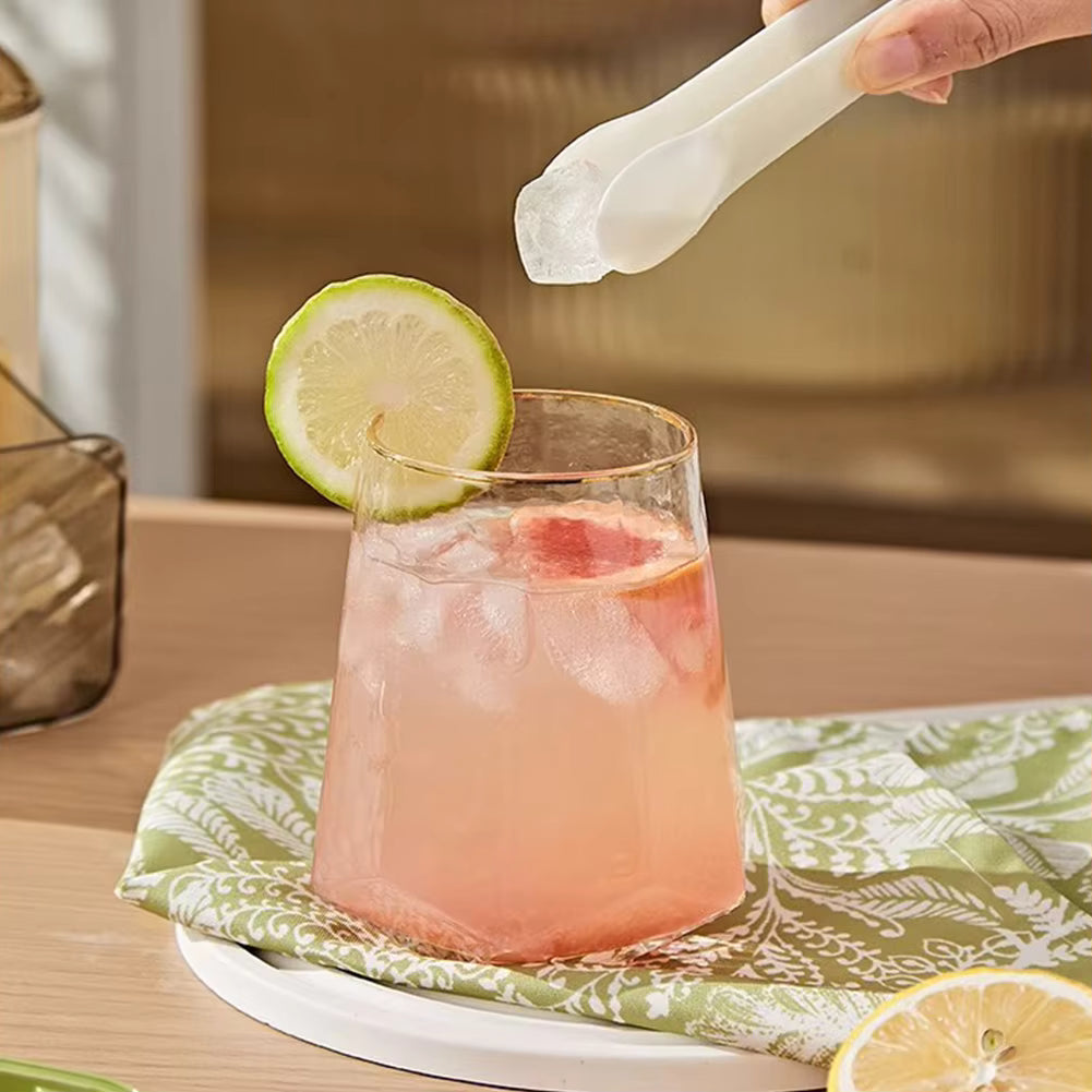 Pink cocktail with lime garnish on a green patterned coaster, with a blurred background.