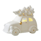 White ceramic car-shaped lamp with a wreath on top, glowing from within.