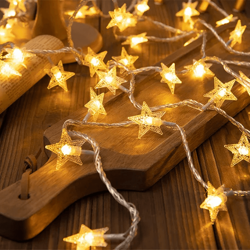 Warm white star-shaped string lights draped over a wooden cutting board on a rustic wooden table.