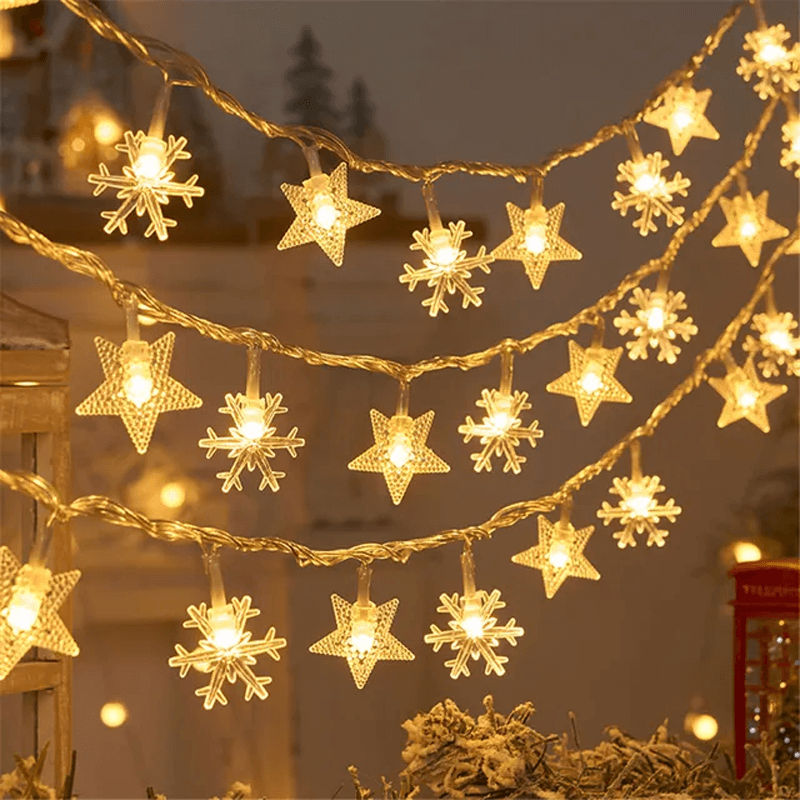 String lights with star and snowflake designs on a blurred outdoor background