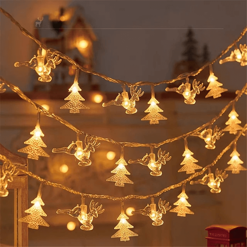 Warm white Christmas string lights shaped like trees, reindeer, and stars, draped in multiple rows against a softly blurred holiday background.