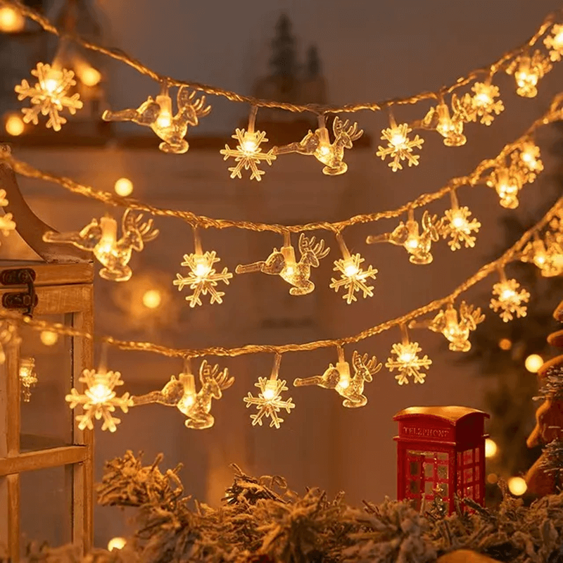 Decorative string lights with reindeer and snowflake designs hanging above a Christmas tree.