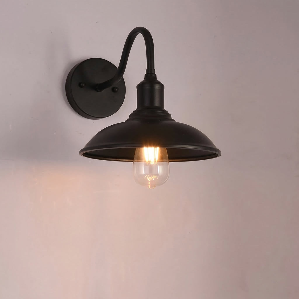 Black wall-mounted lamp with a lit bulb on a plain background