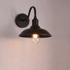 Black wall-mounted lamp with a lit bulb on a plain background