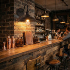 Bar counter with copper bar tools and bottles against a brick wall.